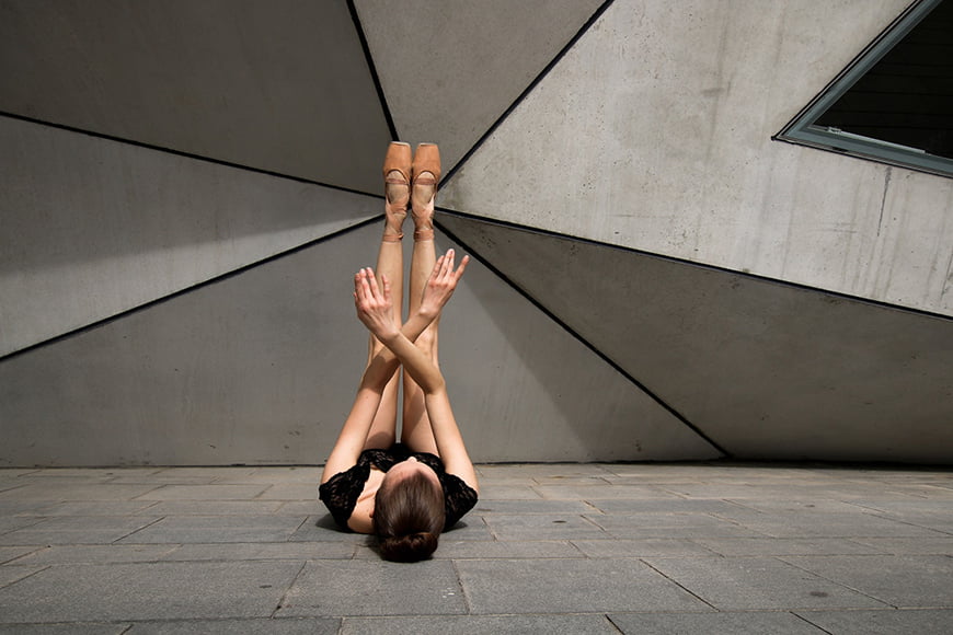 Ballet model pose against modern architecture backdrop.