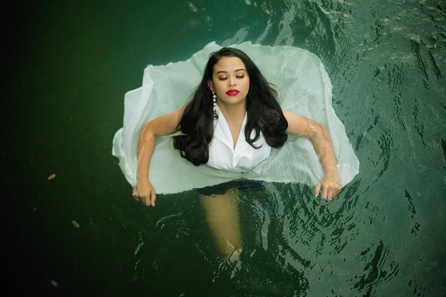 A photography shoot with a glamorous women standing in water