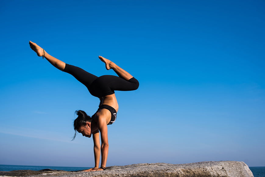 A women doing a yoga pose on a rock cliff