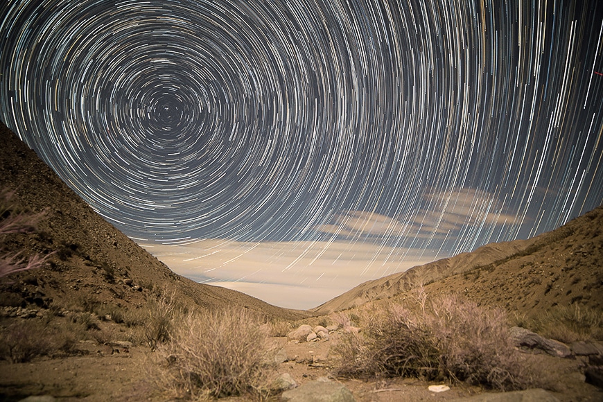 Star trails in the sky over a rocky dry landscape