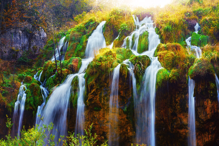 Image of a beautiful water fall flowing down green nature and trees