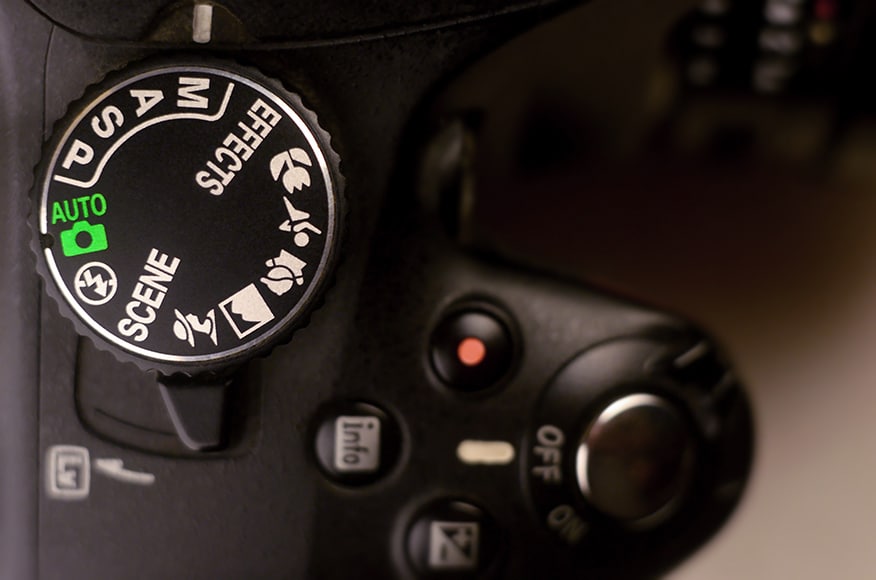 Close-up macro shot of a modern digital SLR camera. Detailed photo of black camera body with buttons to control and switch shooting modes