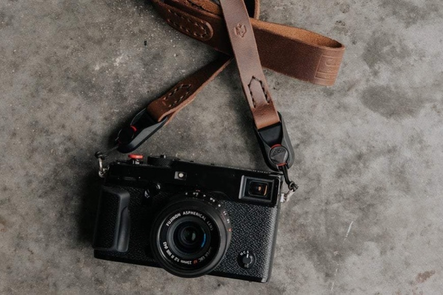 camera with leather strap attached on table