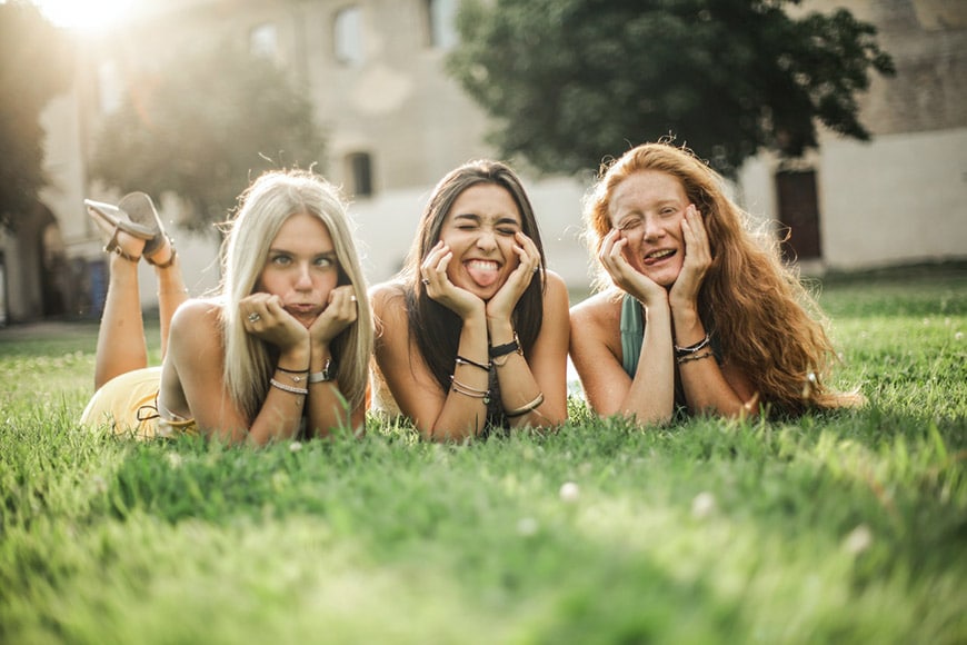 Three girls posing on grass making funny faces