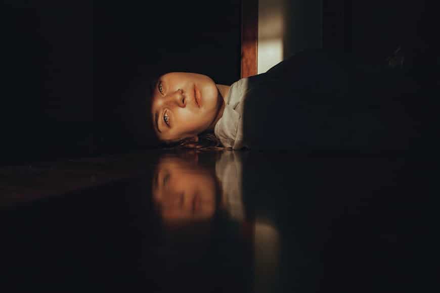 Woman lying in shadow with reflection on floor