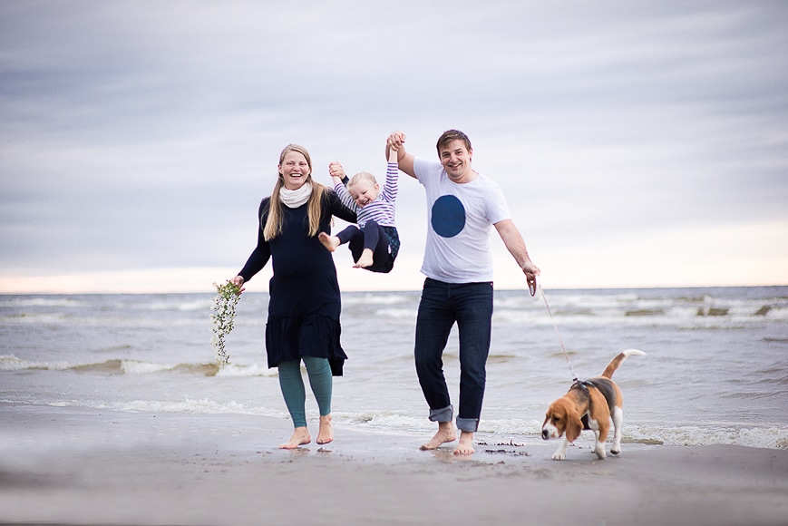 Lifestyle shot of parents with their baby and dog at the beach