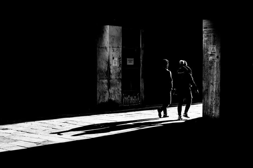 Two subjects walking through a doorway with shadows