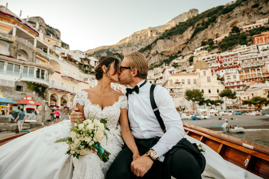 A bride and groom kissing on a boat in positano.