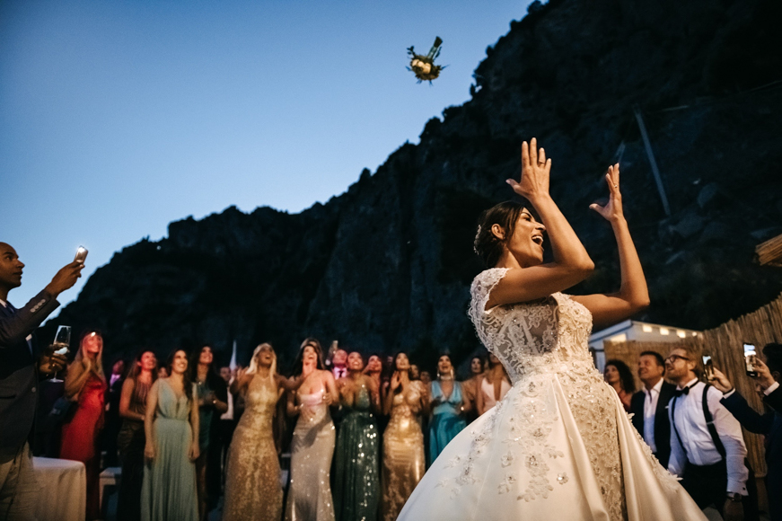 A bride throws a bouquet to the crowd at a wedding.