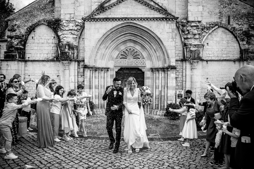 A bride and groom exiting a church in a black and white photo.
