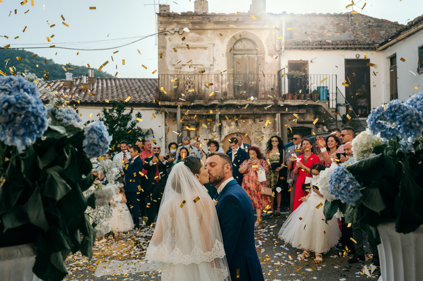 A bride and groom are surrounded by confetti at their wedding.