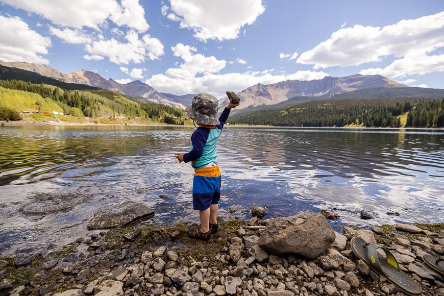 Child playing with stones at mountain lake