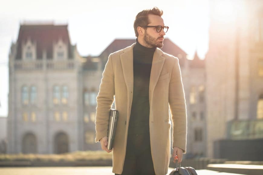 Man in camel coat and glasses