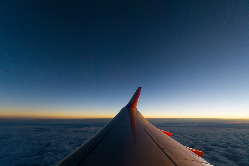 Airplane wing over cloudy horizon