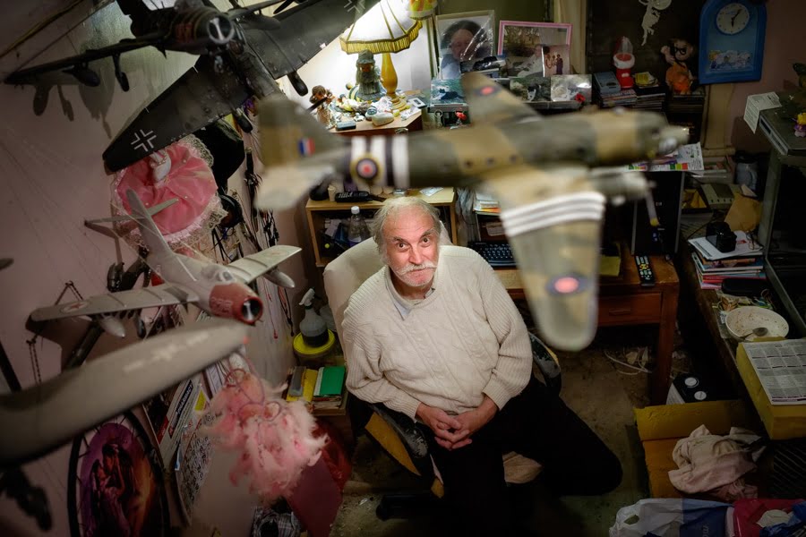 a man sitting in a chair in a room filled with toys.