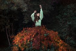 a woman standing on top of a pile of leaves.