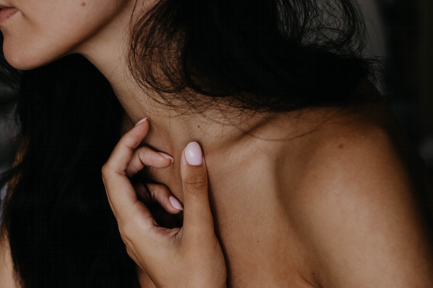 a close up of a person touching her neck.