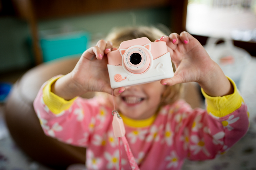 a little girl holding up a camera to take a picture.