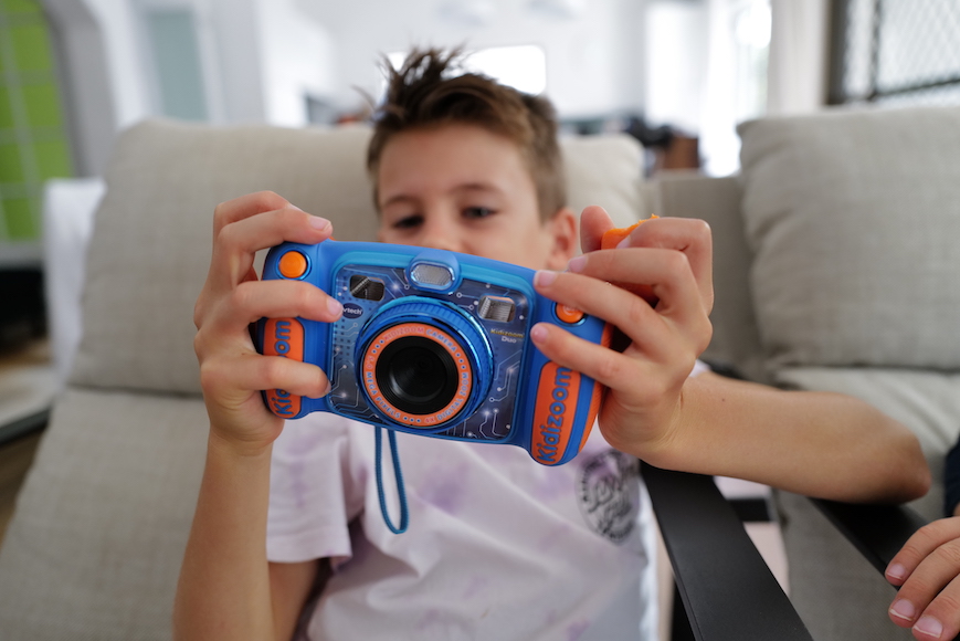 a young boy holding a blue and orange camera.