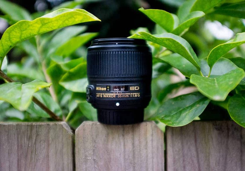 a camera lens sitting on top of a wooden fence.