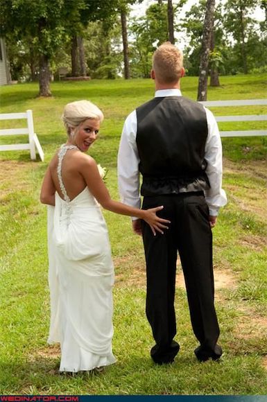 a Bride touching grooms bottom standing in a field.