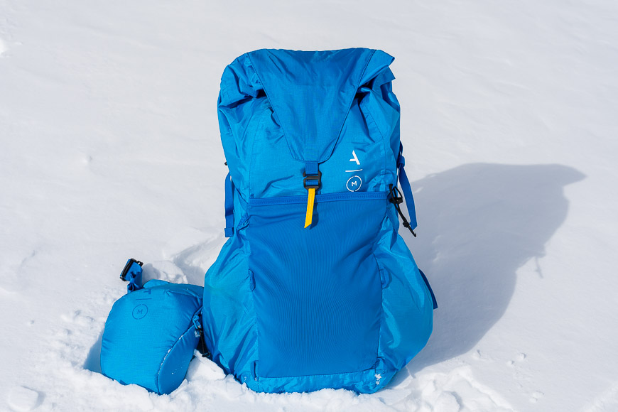 a blue backpack sitting on top of snow covered ground.