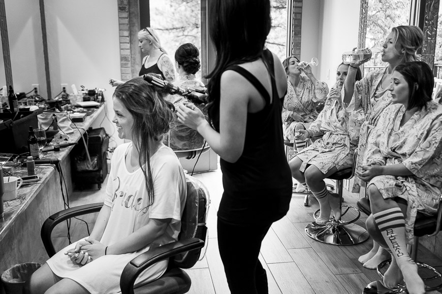 a black and white photo of a woman getting her hair done.