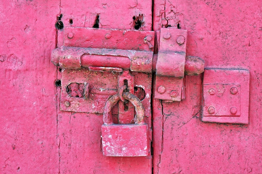a close up of a pink door with a padlock.