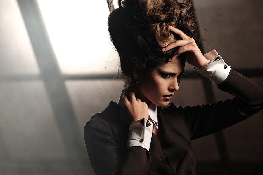 a woman in a suit is holding her hair.