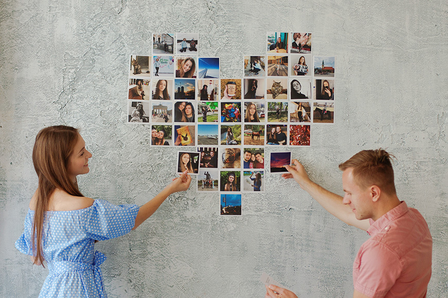 a man and a woman pointing at a wall with pictures on it.