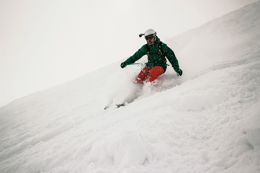 a man riding skis down a snow covered slope with a go pro camera.