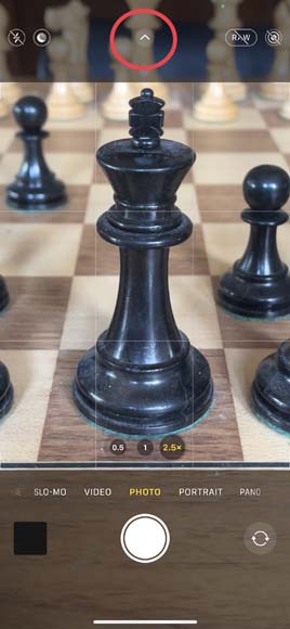 A screenshot of the iPhone camera app showing a highlight of the menu button and a close up of a chess board with pieces on it.