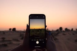 a person taking a picture of a sunset using their iPhone.