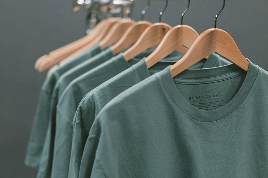 a row of green shirts hanging on a rack.