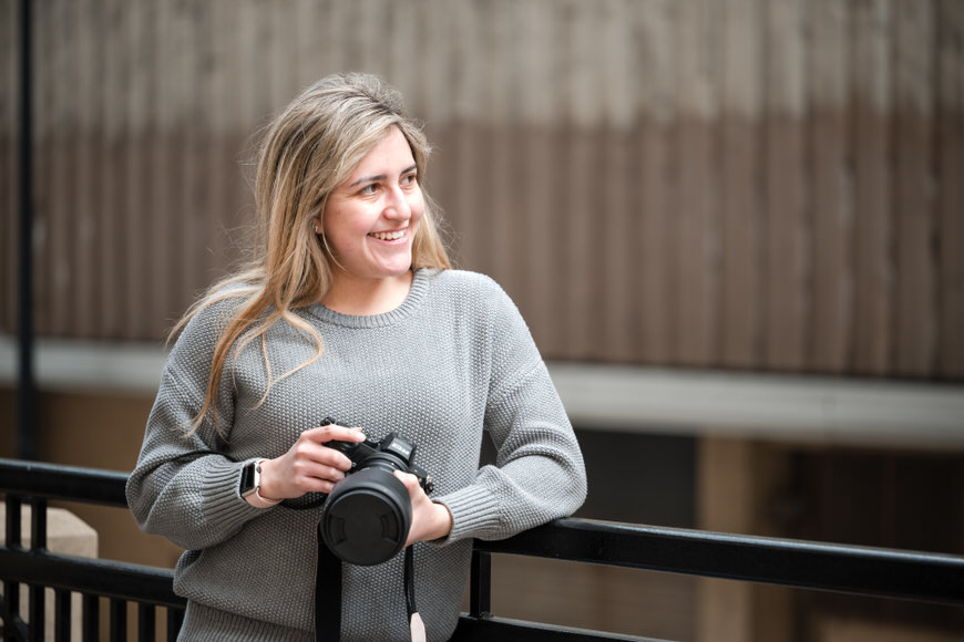 a woman is holding a camera and smiling.