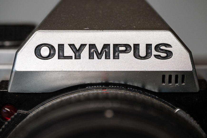 a close up of an Olympus film camera with a lens.