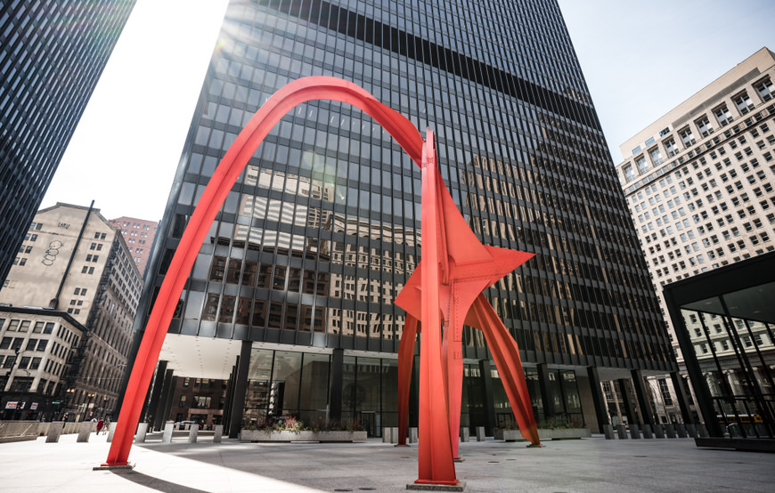 a large red sculpture in front of a tall building.