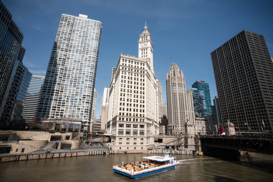 a boat traveling down a river next to tall buildings.