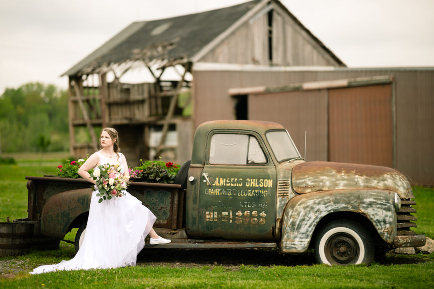a bride sitting on the back of an old truck.