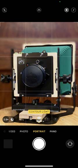 screenshot of Portrait Mode on iPhone showing a picture of a camera on a wooden table.