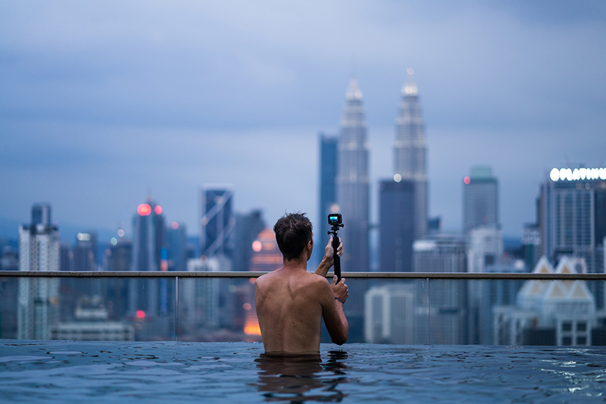 a man taking a picture of a city from a swimming pool.