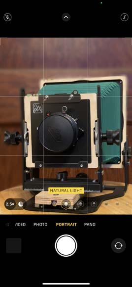 screenshot of Portrait Mode on iPhone showing a picture of a camera on a wooden table.