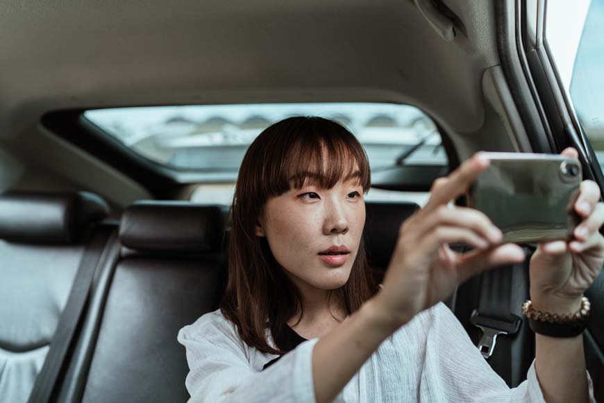 a woman sitting in a car holding a cell phone.