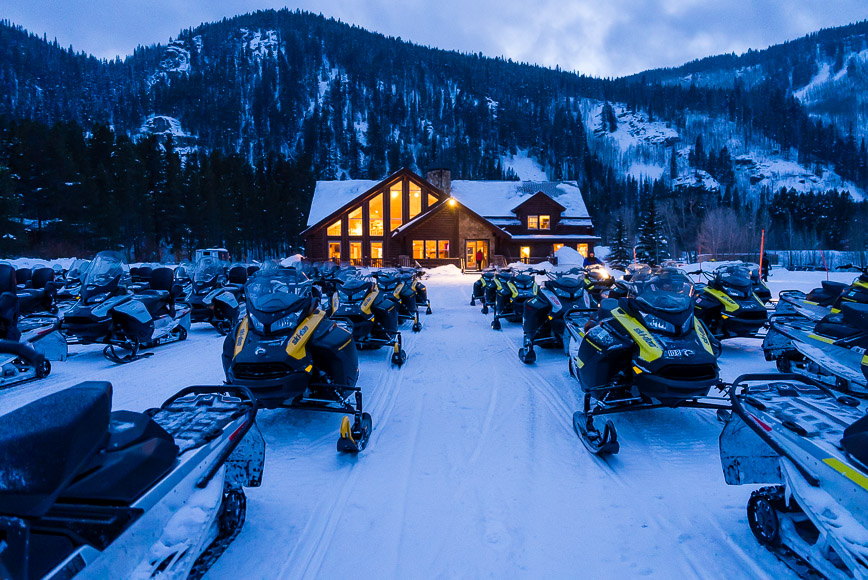a lot of snowmobiles parked in front of a house.
