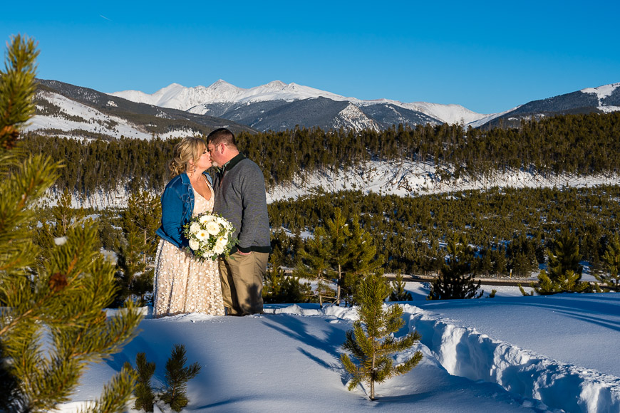 a bride and groom kissing in the snow.