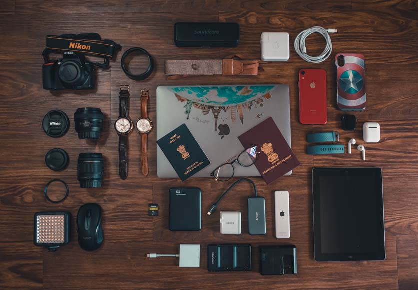a wooden table topped with lots of different items including camera gear and passports.