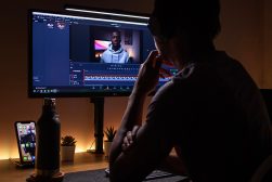 a man sitting in front of a computer monitor editing youtube videos.