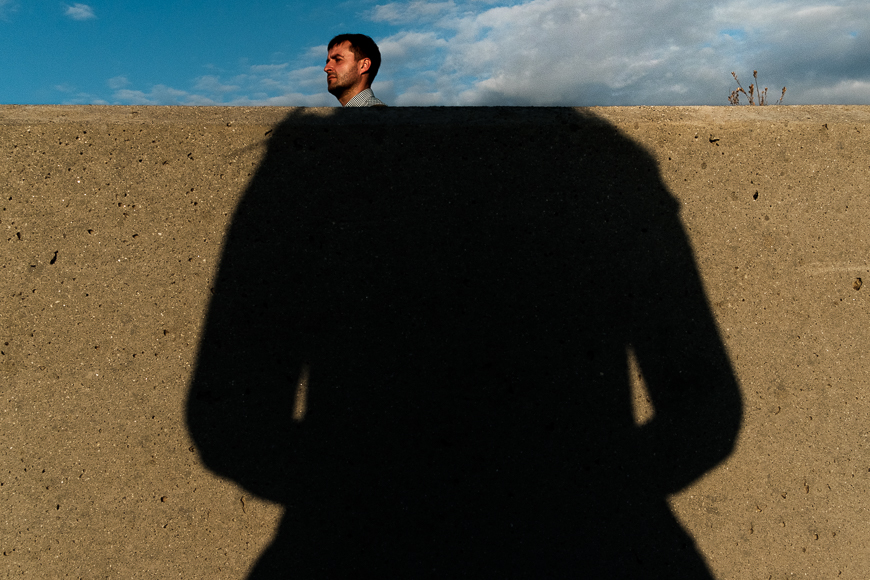 a shadow of a man standing in front of a cement wall.