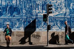 a man walking down a sidewalk next to a blue wall.