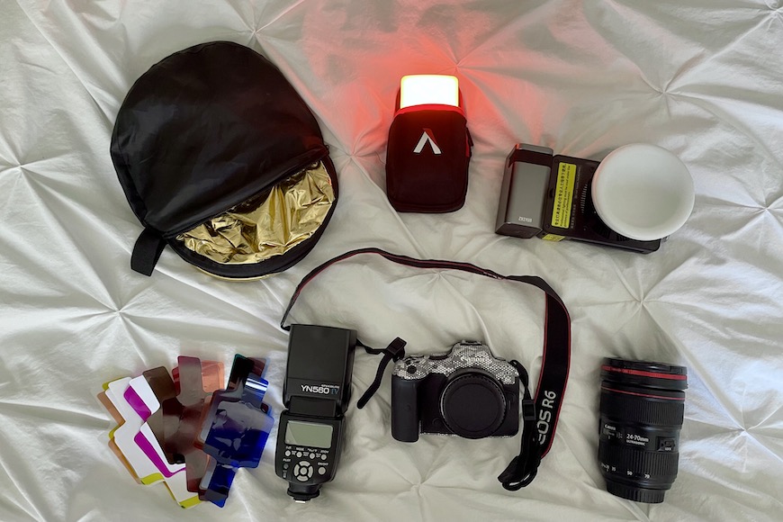 the contents of a camera bag laid out on a bed.